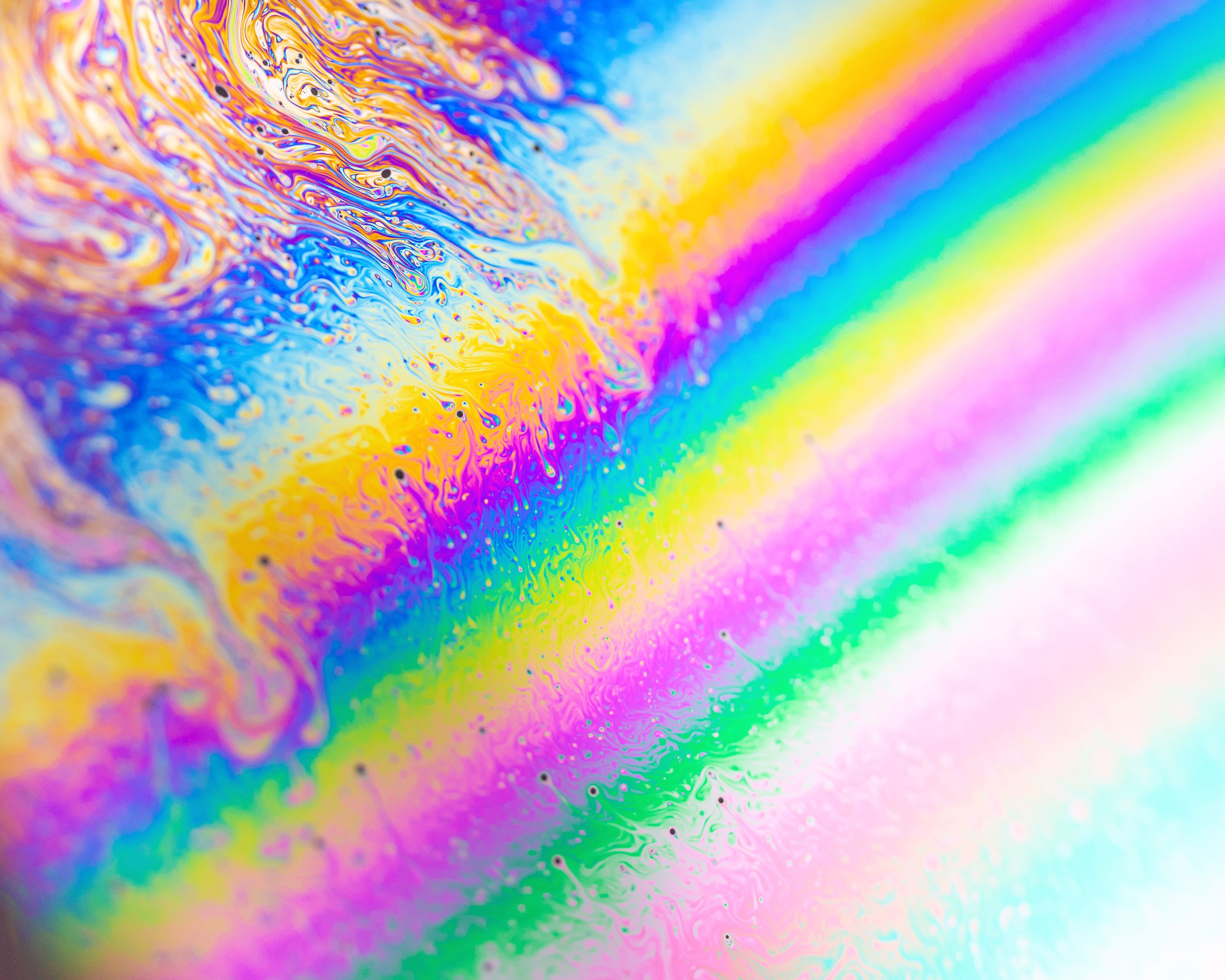 Vibrant abstract image of swirling rainbow-like liquid reflections showcasing dynamic patterns and bold colors.